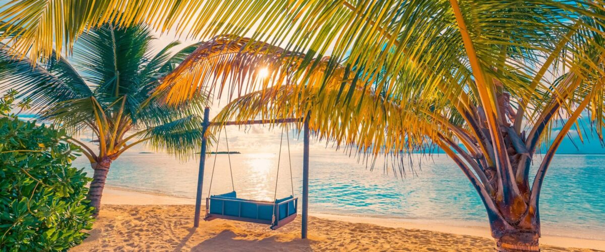 Tropical sunset beach background as summer landscape panorama with beach swing or hammock and white sand and calm sea beach banner. Perfect beach scene vacation or summer holiday tourism concept